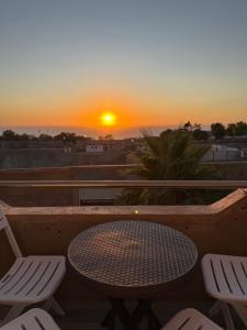 a table and chairs on a balcony with a sunset at Casa Mare Oureah in Mazagran
