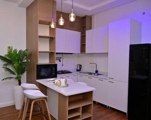 a kitchen with white cabinets and a black refrigerator at TM Homes in Abuja