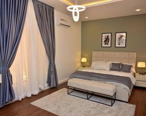 a bedroom with a large bed and blue curtains at TM Homes in Abuja