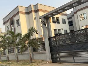 a building with a gate and palm trees in front of it at TM Homes in Abuja