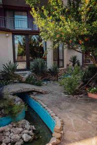a garden with a bridge over a stream in front of a house at Coral Guest House in Obzor