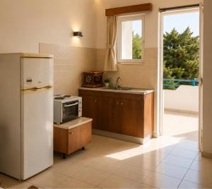 a kitchen with a refrigerator and a sink at Merryland Studios & Apartments in Kremasti