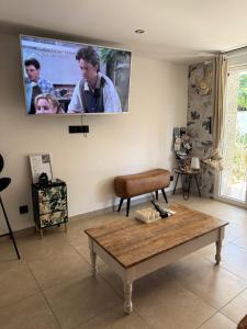 a living room with a table and a tv on the wall at Superbe T2 au rez-de-chaussée avec jardin in Arles