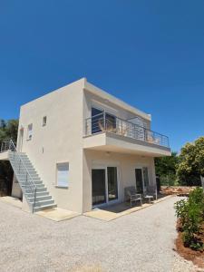 a large white house with a balcony and stairs at BLV Apartments in Tsoukalades