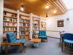 a library with blue chairs and bookshelves at Haslibergoase in Hasliberg