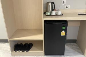 a small black refrigerator in a cabinet next to a desk at Baan Thanakul Suvarnabhumi in Ban Khlong Nong Pru