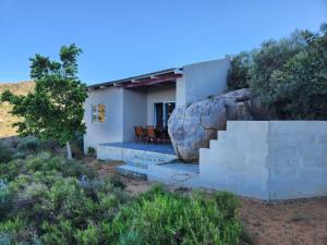 a small white house with a large rock at Katkop Resort in Graafwater