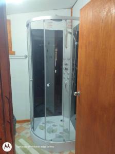 a glass shower in a bathroom next to a wooden door at Departamento con tinaja in Llanquihue +16 photos