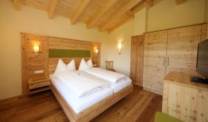 a bedroom with a large white bed and a television at Alpenperle in Ramsau am Dachstein