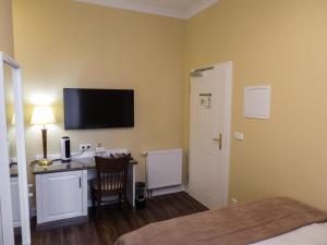 a room with a desk with a computer and a television at Fründts Hotel in Wismar
