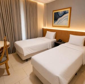 a hotel room with two beds and a table at Hotel Del Rey by Poty - RUA XV DE NOVEMBRO in Curitiba