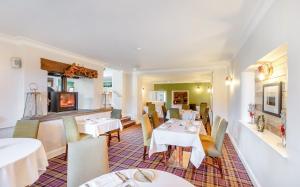 a restaurant with white tables and chairs and a television at Banbury Wroxton House Hotel in Banbury
