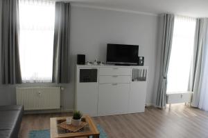 a living room with a tv on a white cabinet at Am Seeufer 59a Fewo 9 in Waren