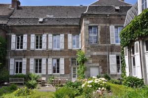 una vieja casa de ladrillo con un jardín delante de ella en La Fumacienne en Fumay