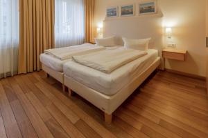 a bedroom with a large bed with white sheets at Hafendomicil Appartement WH05 - Maus in Waren