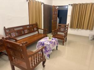 a room with three benches and a table with a plant at Rainbow721 in Pondicherry