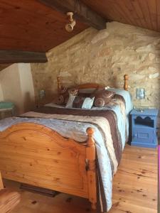 a bedroom with a wooden bed and a stone wall at Les Mialles in Prayssac
