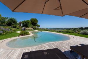 a swimming pool in a backyard with an umbrella at Villa Pietrarosa by MMega in Cascina Monte Serico