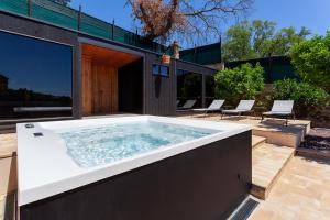 a large hot tub on a patio with chairs at Villa Pietrarosa by MMega in Cascina Monte Serico +37 photos