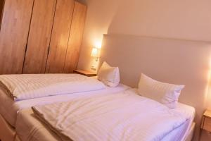 a bedroom with two beds with white sheets and pillows at Hafendomicil Appartement WH13 - Eisvogel in Waren