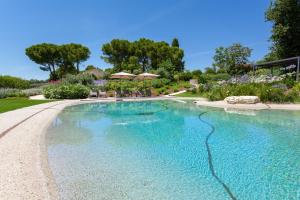 a swimming pool with blue water in a yard at Villa Pietrarosa by MMega in Cascina Monte Serico