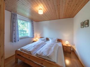 a bedroom with a bed with white sheets and a wooden ceiling at Luett Huus in Lärz