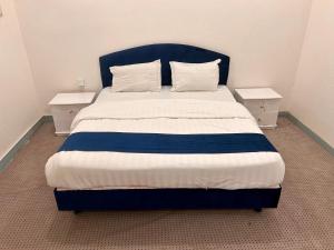 a bed with a blue headboard and two night stands at الكرامة للشقق المفروشة in Abha