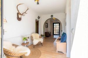a living room with white furniture and a hallway at Die Jagdhütte in Dedelow