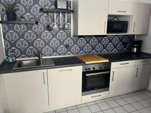 a kitchen with white cabinets and a sink at WarenERleben in Waren