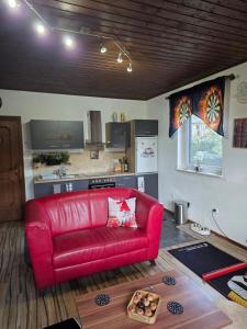 a red couch in a living room with a kitchen at Ferienwohnung Köck in Sankt Georgen bei Neumarkt