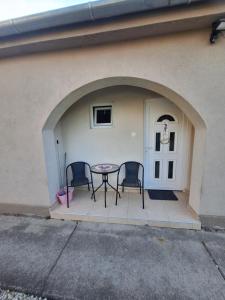 a patio with two chairs and a table in front of a building at Levendula Porta in Balatonfůzfő