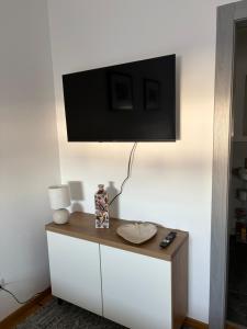 a tv on a wall above a white cabinet at Ferienwohnung Mia in Büchlberg