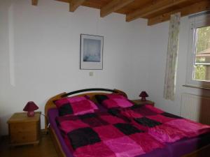 a bedroom with a bed with a pink and black comforter at Ferienhaus Jabel 24 in Jabel +1 photo