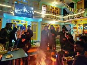 a group of people standing around a fire in a bar at LAP Stays - Wanderer's Nest in Chitkal