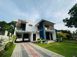 a white house with a car parked in the yard at US Apartment in Nochchiyagama