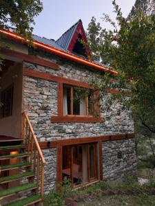 a stone house with wooden windows and a staircase at GhratFalls Stone Cottage in Banjār