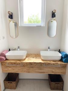 two sinks on a wooden counter in a bathroom with mirrors at ETALON in the heart of Novi Sad in Novi Sad