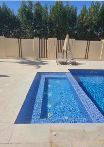 a swimming pool with a chair and an umbrella at Hawana Studio in Salalah