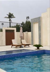 a swimming pool with two lounge chairs and a umbrella at Hawana Studio in Salalah