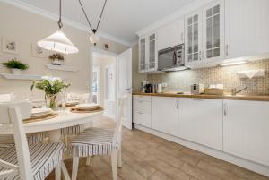 a kitchen with white cabinets and a table and chairs at Lööws Roos in Wenningstedt