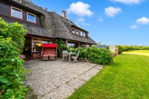 a house with a table and chairs in the yard at Lööws Roos in Wenningstedt