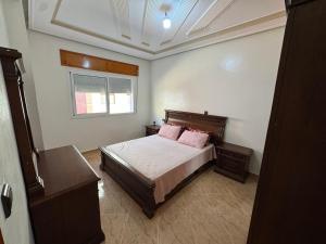 a bedroom with a bed with pink pillows and a window at Larache City Apartment in Larache