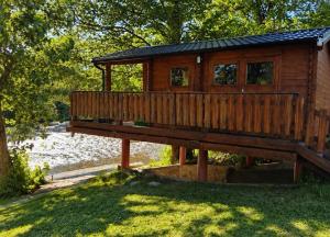 a wooden cabin with a deck in the grass at Domaćinstvo Kondić in Podovi