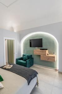 a bedroom with a green couch and a flat screen tv at Barrio La Suite del Borgo Bacoli in Bacoli