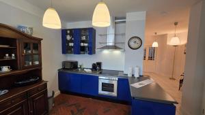 a kitchen with blue cabinets and a clock on the wall at Altstadt Zauber in Waren
