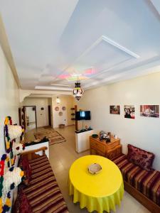 a living room with a yellow table and a couch at Zakar Apartments & Terrace in Mirleft