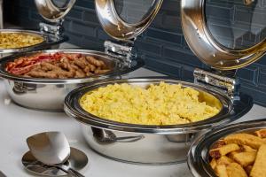 a buffet of different types of food in pans at Hyatt Place Waco/Downtown in Waco