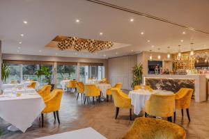 a restaurant with white tables and yellow chairs at Gleddoch Golf & Spa Resort, WorldHotels Distinctive in Langbank