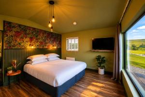 a bedroom with a large bed and a large window at Wild Hideaways Luxury Lodges and Eco Spa in Bantry