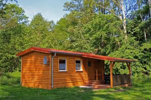 a small wooden cabin with a porch in the grass at Bungalow Seedorf 4 in Basedow